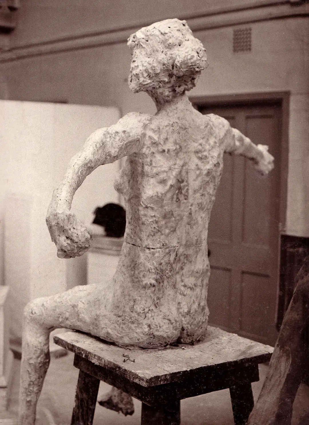 Reverse view of seated figure with outstretched arms