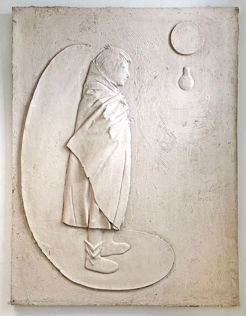 A relief of a standing figure and a lightbulb cast in resin