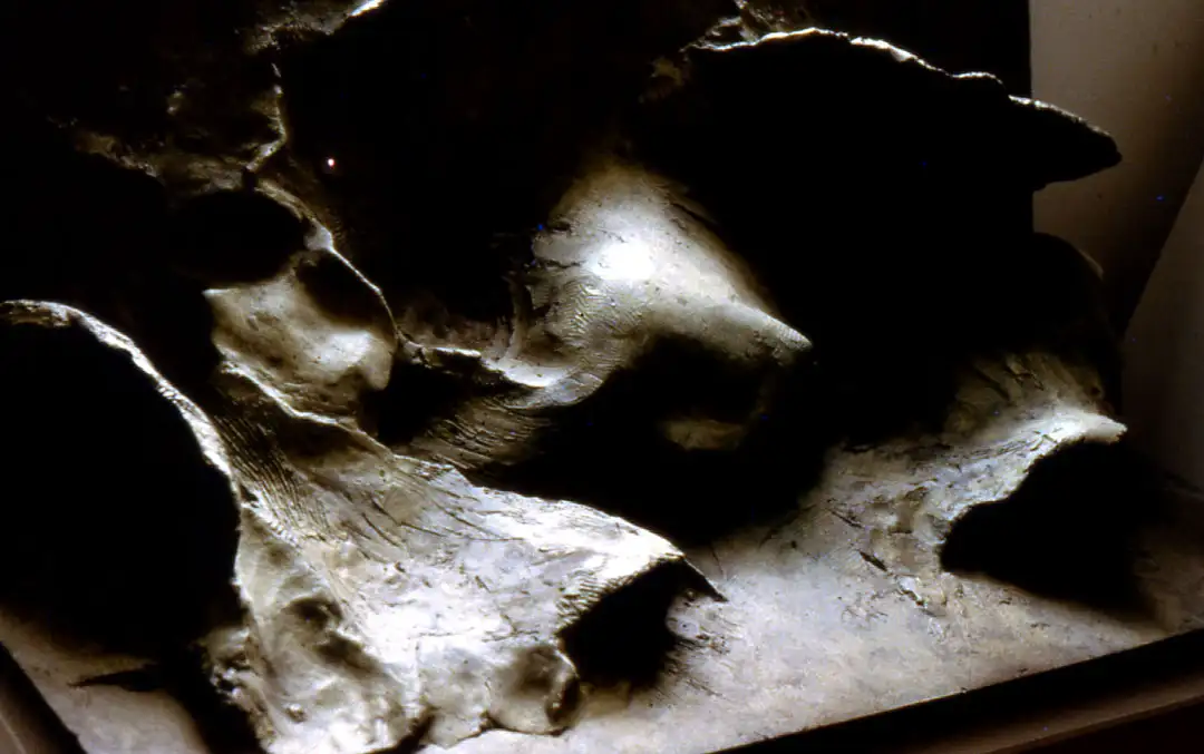 Figure enveloped in waves II, relief in bronze